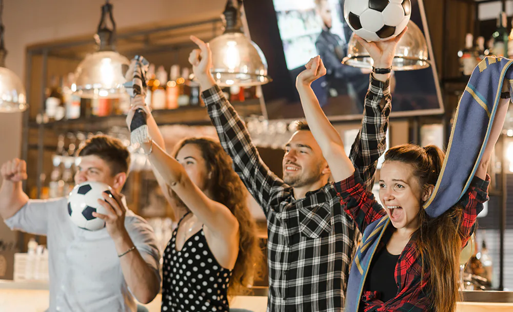 group_friends_watching_sport_together_celebrating_victory_bar.webp